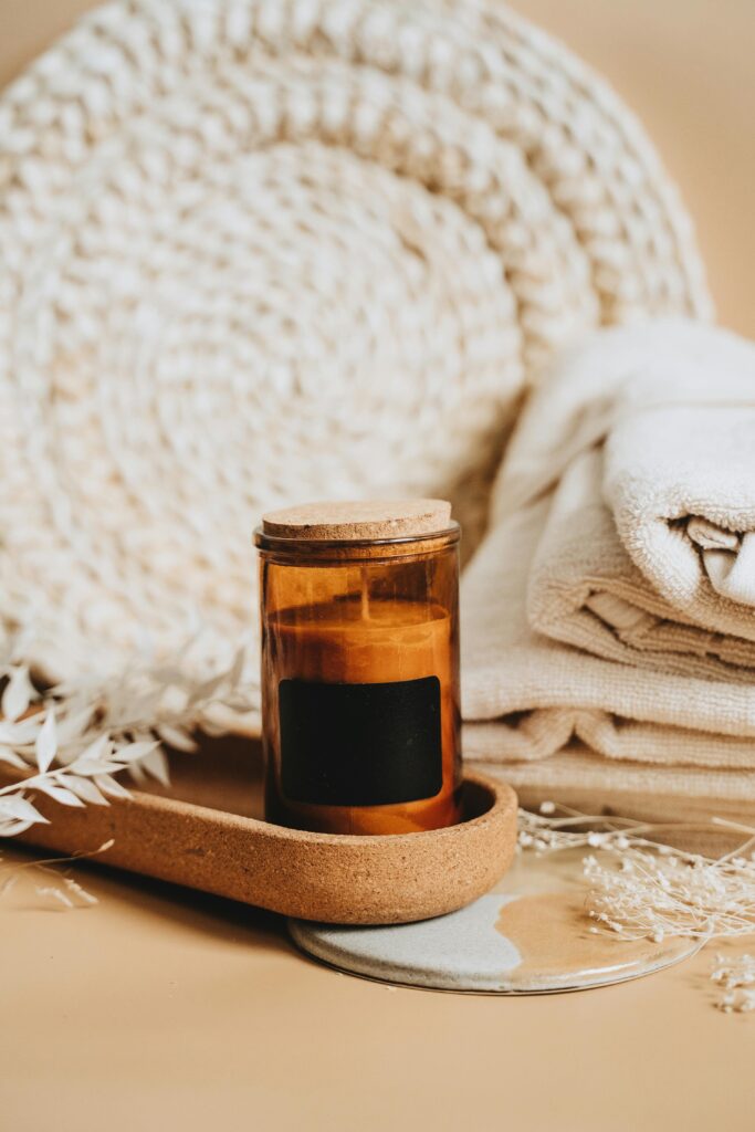 Elegant amber candle with cozy neutral decor setup, perfect for spa or relaxation themes.